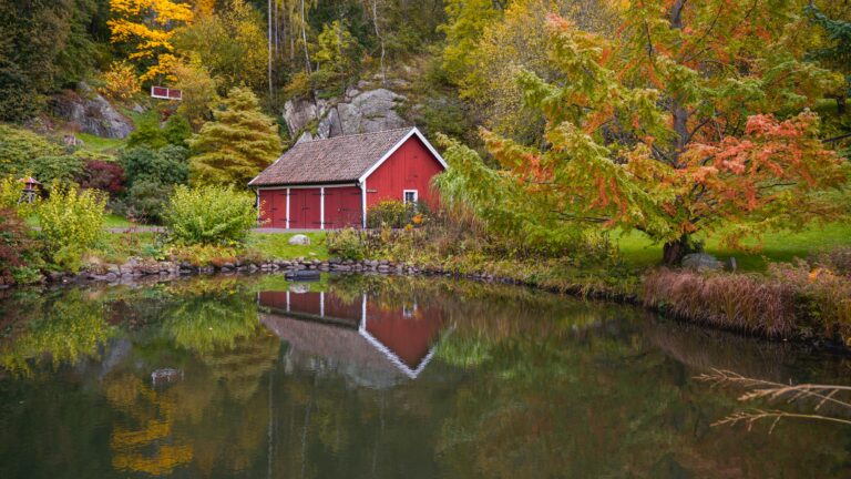 Red wooden cottage by a lake — a classic choice when you rent a Swedish stuga